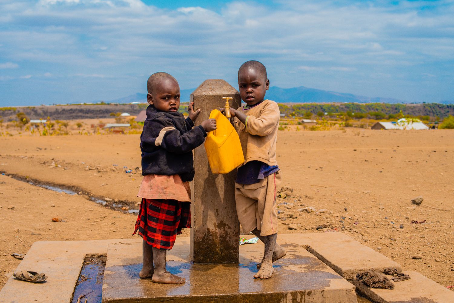 Kinder holen Wasser an einer öffentlichen Wasserstelle
